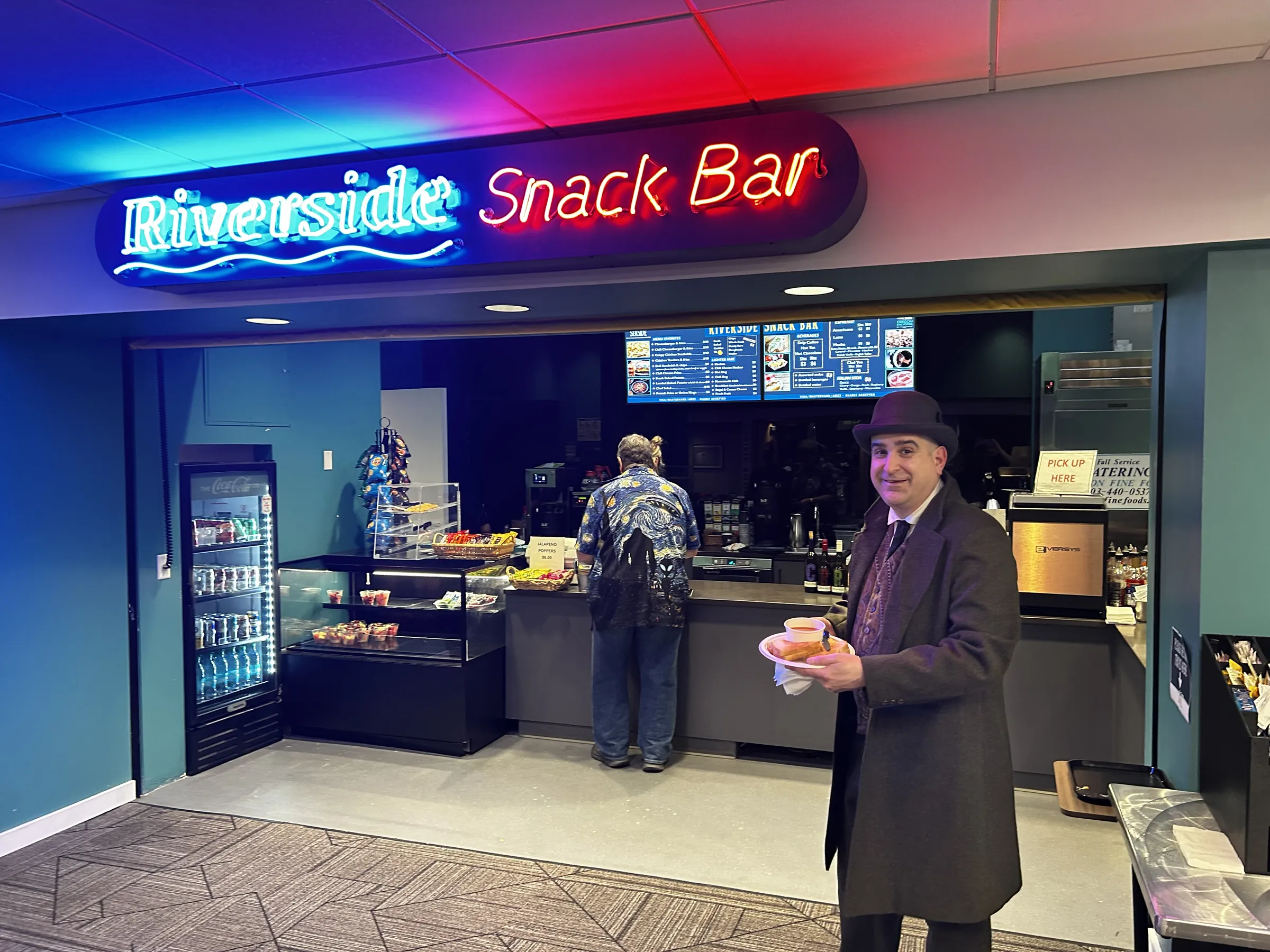 The Riverside Snack Bar neon sign glowing over the concessions counter
