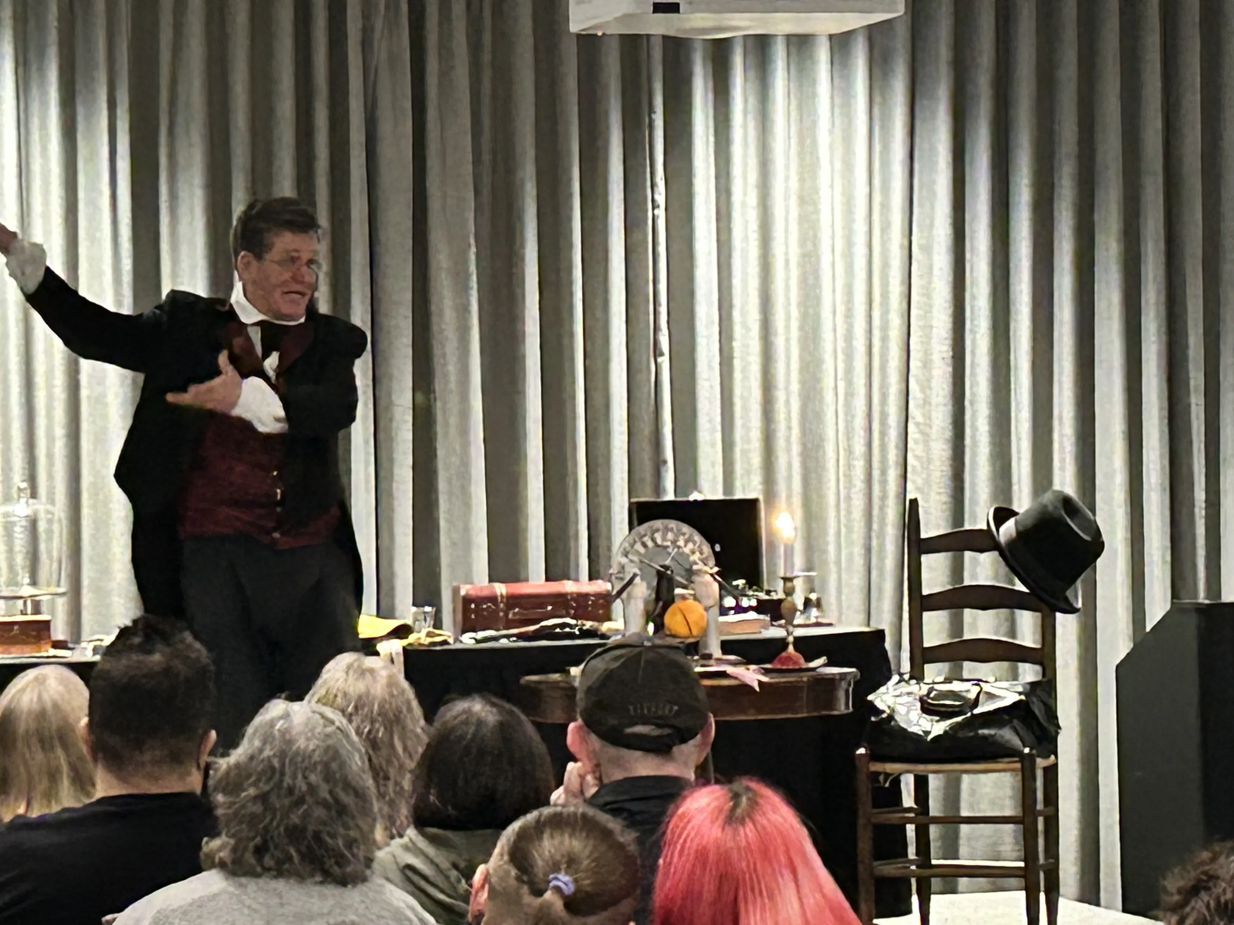 A costumed Victorian conjurer performing at an evening seance show