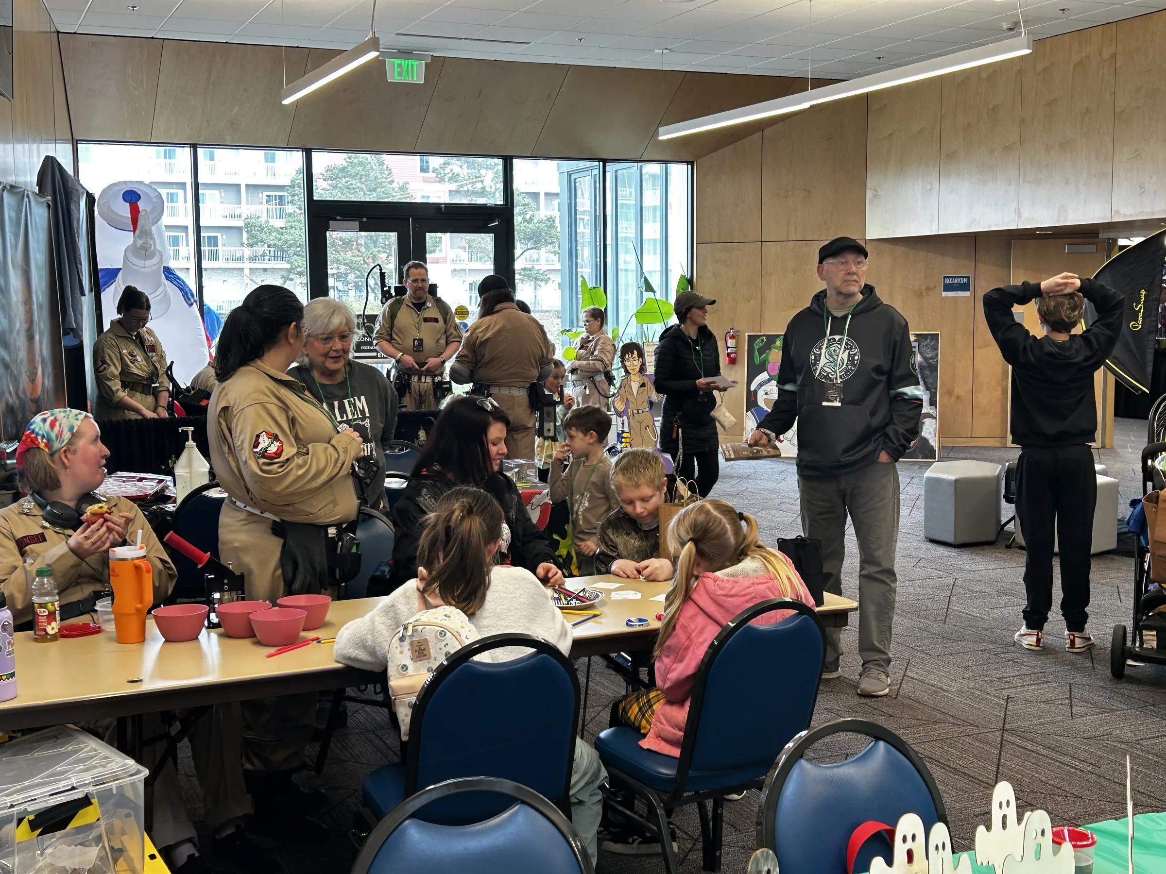 Kids making crafts at the Kids Zone tables with Ghostbusters-suited volunteers