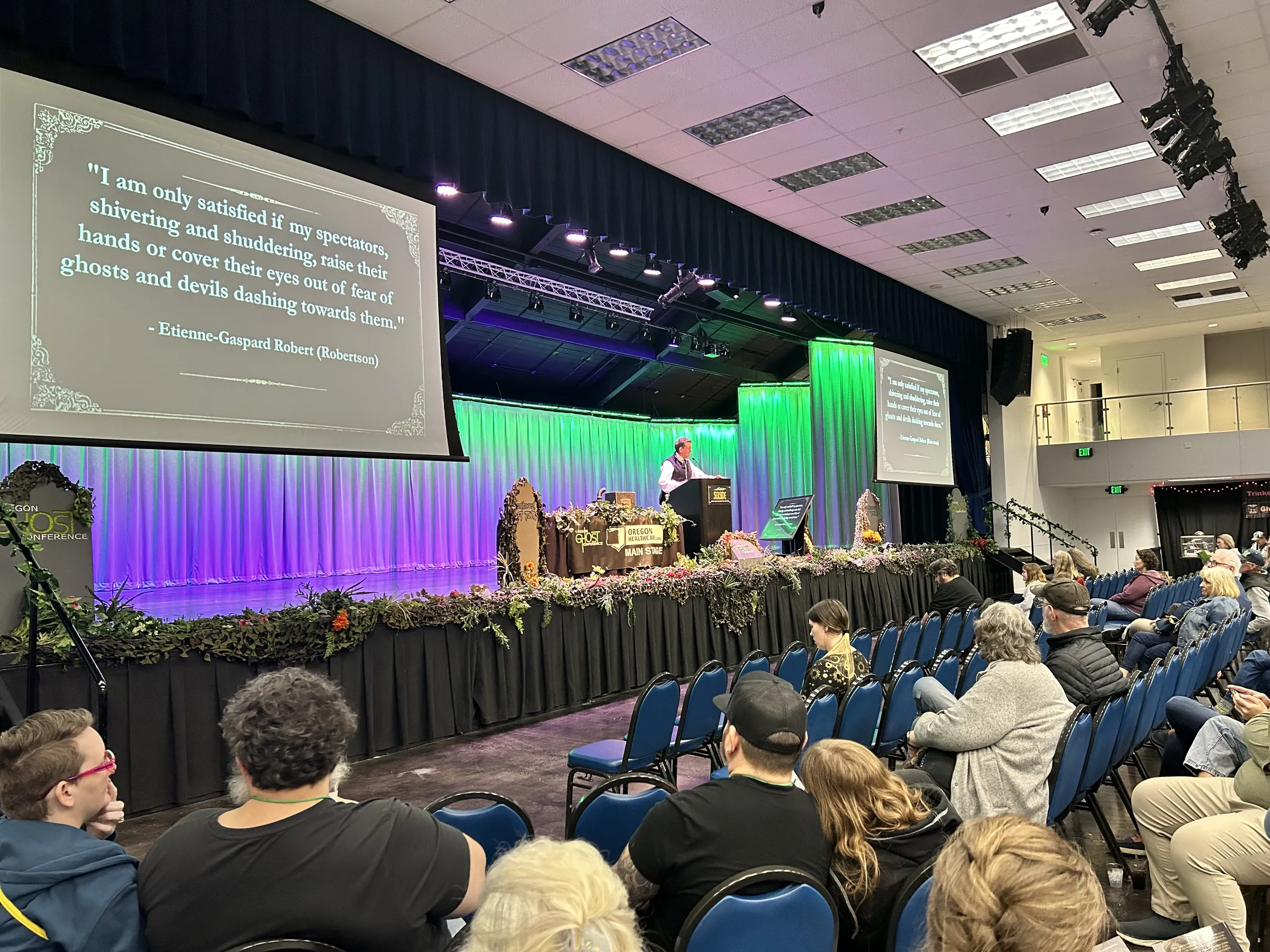 The main stage during a talk, lit green and purple over a full audience