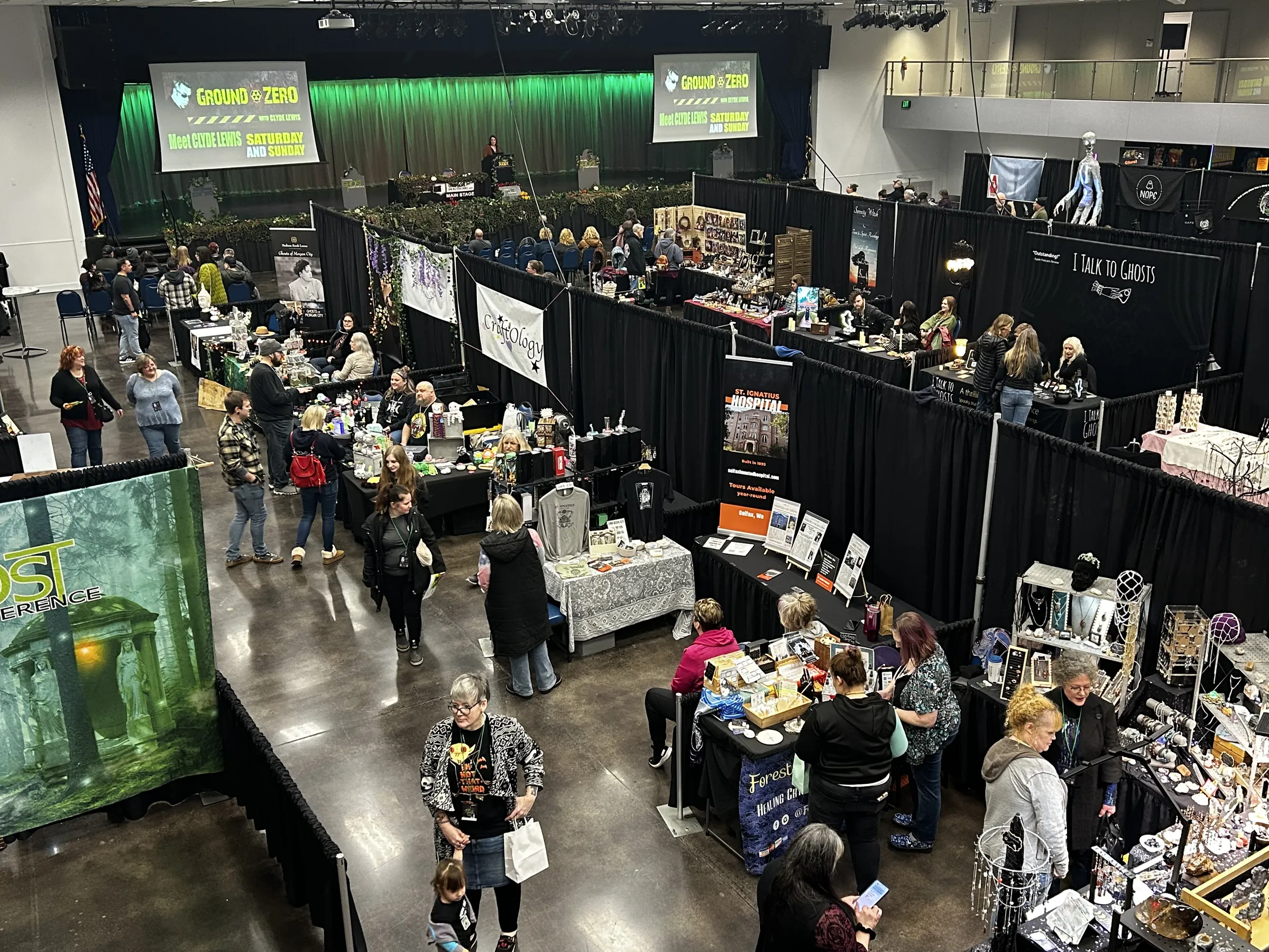 The vendor hall in full swing, seen from the balcony under the green glow of the main stage